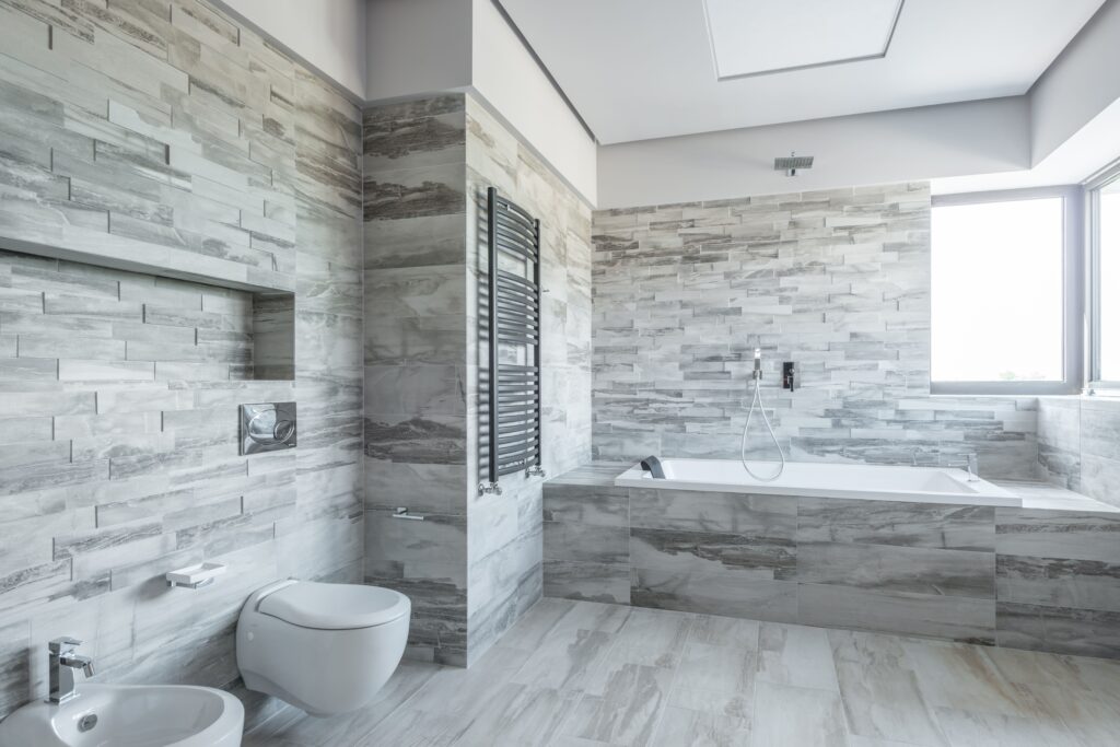 A spacious and stylish bathroom featuring modern design elements like a sleek bathtub and stone tiles.